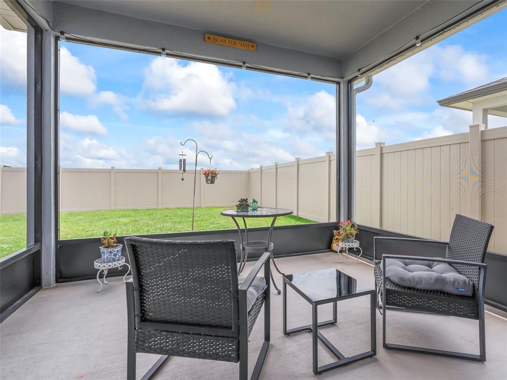 A screened-in patio features two chairs, a small table, and a view of a fenced yard — 2133 TENNESSEE STREET, SUMTERVILLE, FL