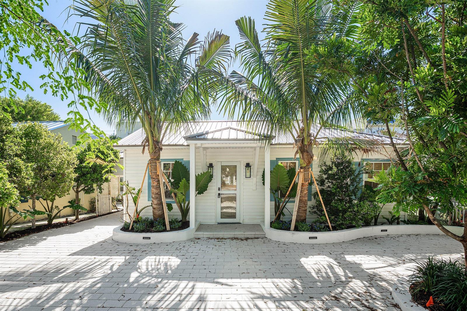 A white cottage with a metal roof, palm trees, and a paved driveway — 23 S Swinton Avenue, Delray Beach FL 33444, DELRAY BEACH, FL
