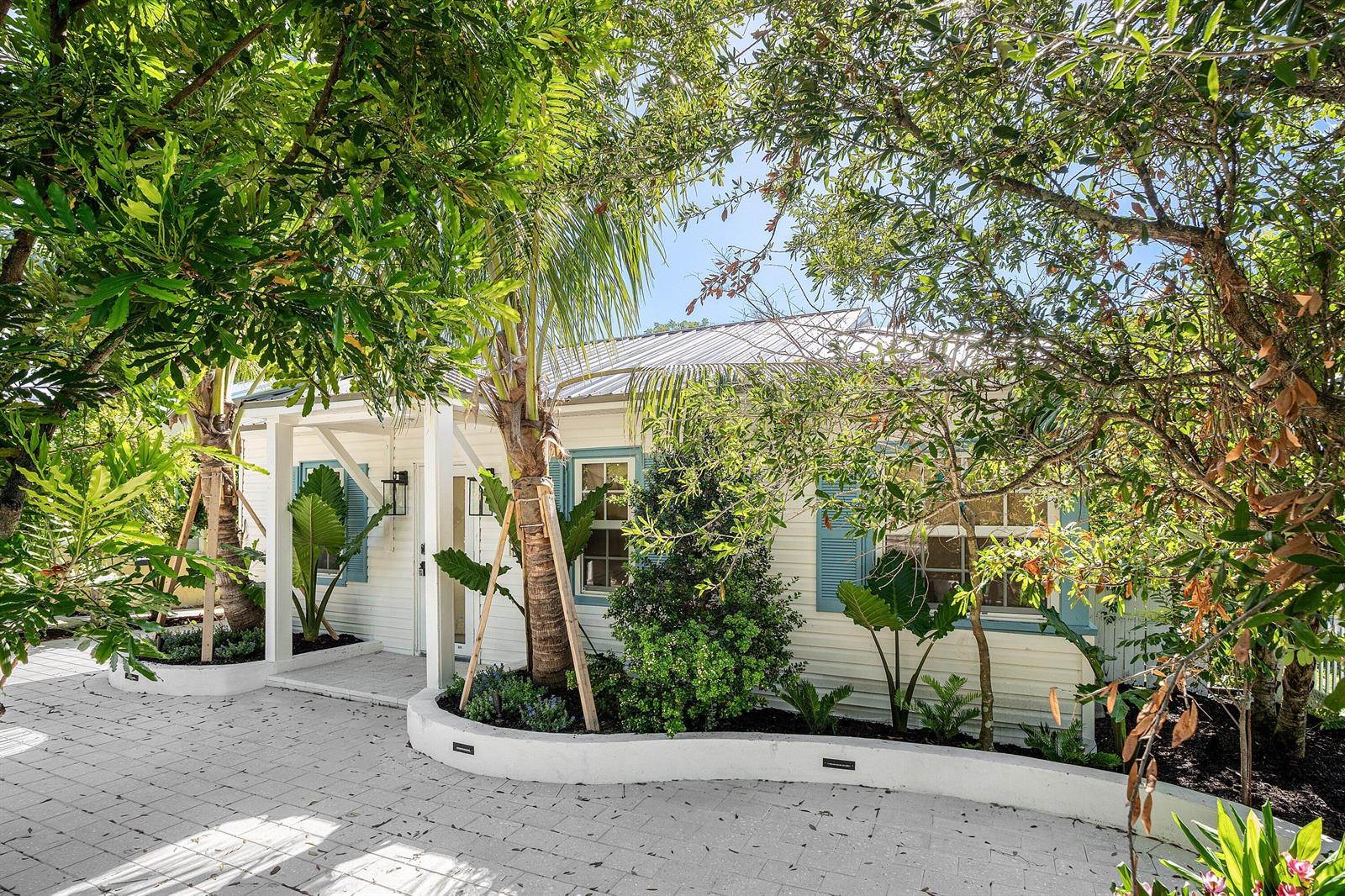 A white cottage with blue shutters and a metal roof sits behind a paved driveway — 23 S Swinton Avenue, Delray Beach FL 33444, DELRAY BEACH, FL