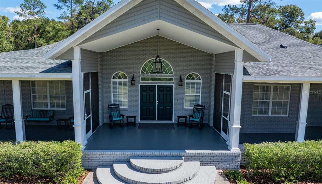 An exterior view of a gray brick house with a covered porch and double doors — 1237 SW OLD LAKE CITY TERRACE, HIGH SPRINGS, FL