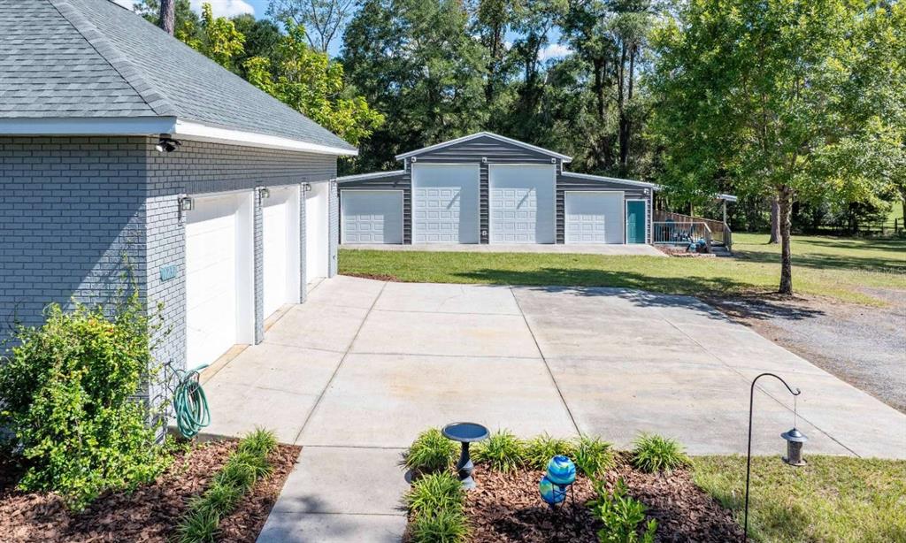 A gray brick house with a three-car garage faces a detached three-bay metal workshop — 1237 SW OLD LAKE CITY TERRACE, HIGH SPRINGS, FL