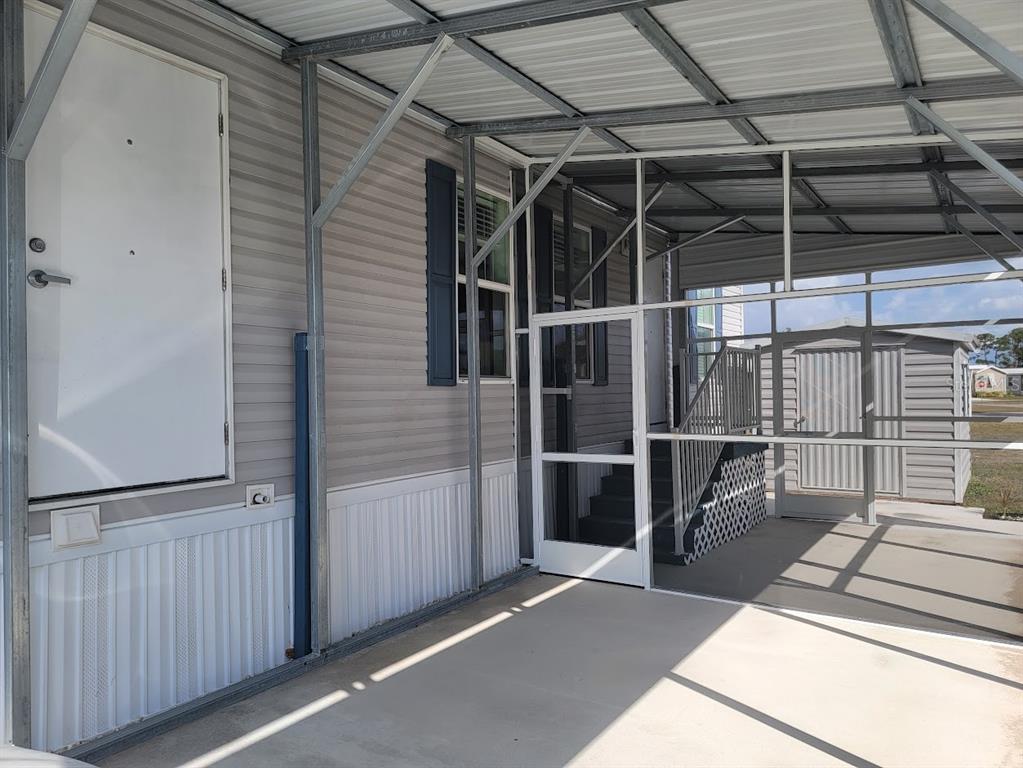 A covered carport area features a white door, a screened-in porch, and a storage shed — 5700 HOLIDAY PARK BOULEVARD, NORTH PORT, FL