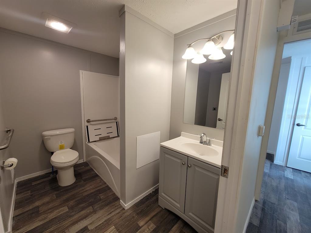 A bathroom features a toilet, a bathtub with a grab bar, and a gray vanity — 5700 HOLIDAY PARK BOULEVARD, NORTH PORT, FL