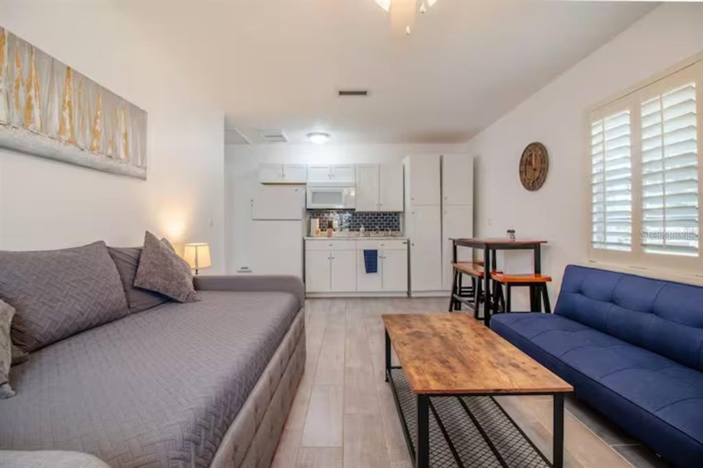 A studio apartment featuring a kitchenette, a gray daybed, a blue sofa, and wood flooring — 3120 PEEL AVENUE UNIT 2, ORLANDO, FL