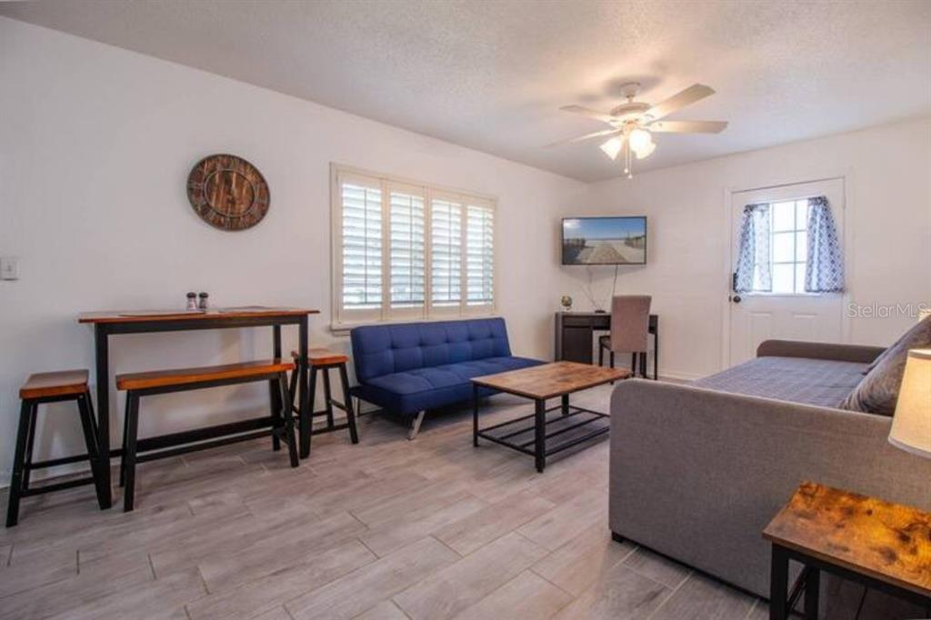 A living room features a blue sofa, a dining table with stools, and light wood flooring — 3120 PEEL AVENUE UNIT 2, ORLANDO, FL