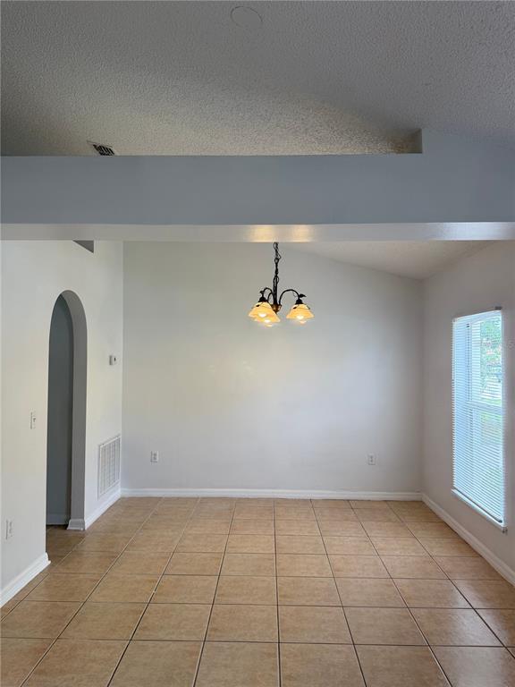 A dining area features tan tile flooring, a vaulted ceiling, and a hanging light fixture — 405 FRANCISCO WAY, KISSIMMEE, FL