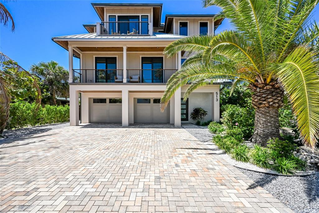 A three-story house with a paved driveway, two garage doors, and a large palm tree — 513 N BAY BOULEVARD, ANNA MARIA, FL
