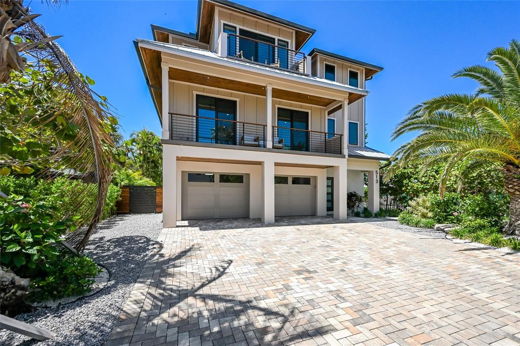 A three-story house with a paved driveway, two garage doors, and two levels of balconies — 513 N BAY BOULEVARD, ANNA MARIA, FL