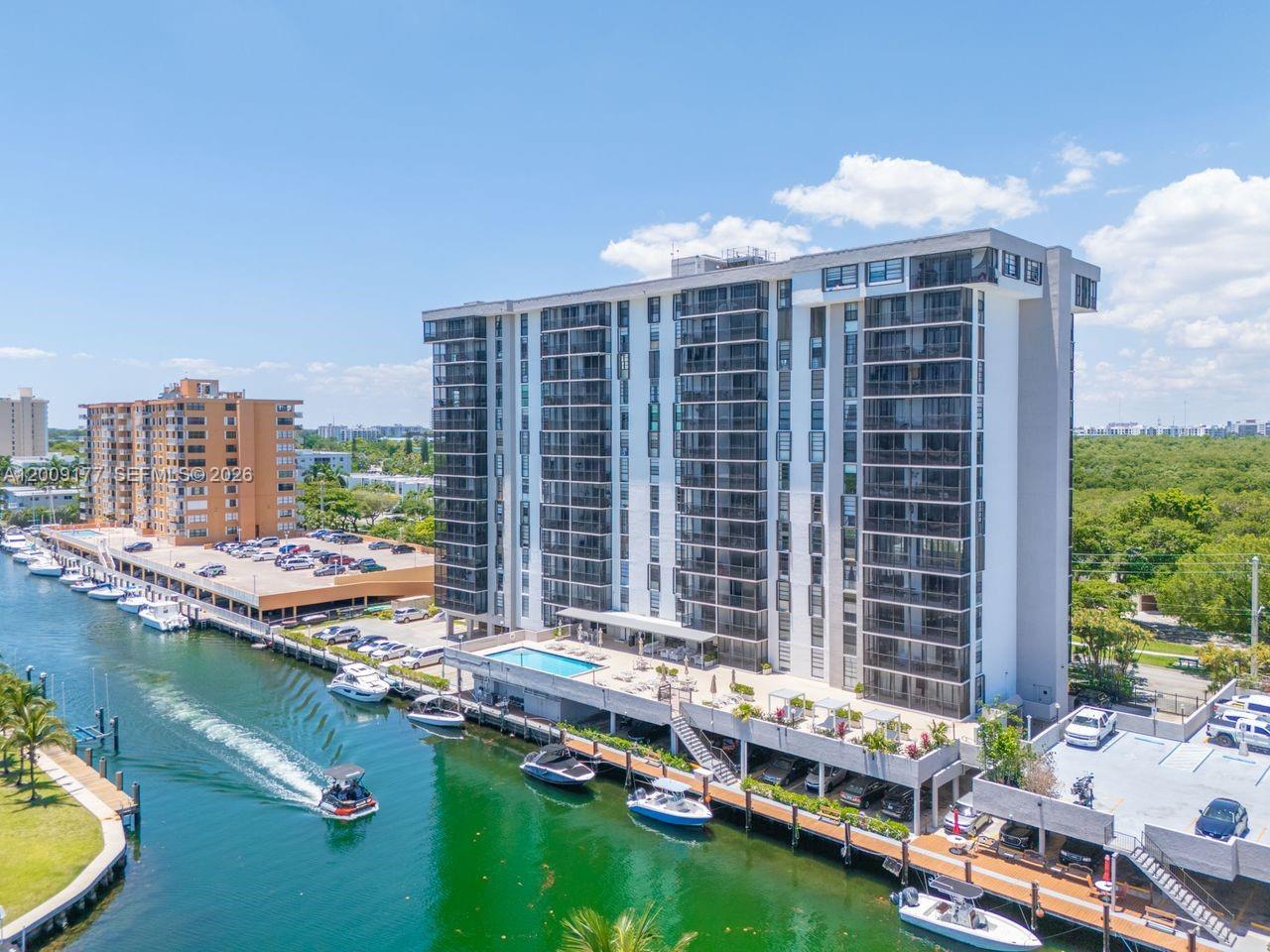 An aerial view shows a tall residential building with a canal, boat slips, and parking — 2500 NE 135th St # C1011, North Miami FL 33181, NORTH MIAMI, FL