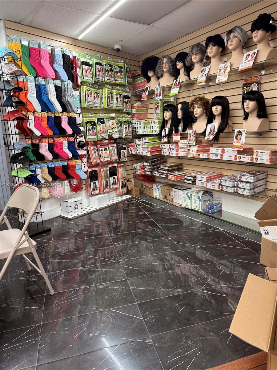A retail store interior features shelves displaying numerous wigs and rows of hanging colorful socks — 715 NE 167th St, North Miami Beach FL 33162, NORTH MIAMI BEACH, FL