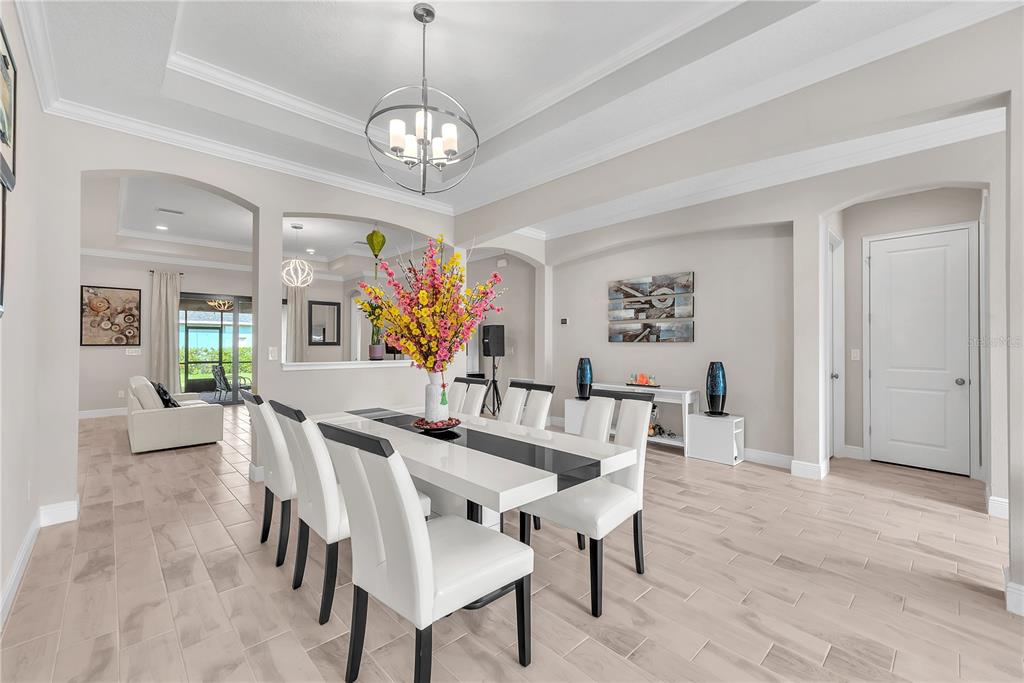 A dining room with a white table, modern chairs, tile floors, and a tray ceiling — 814 TIRANO WAY, SUN CITY CENTER, FL