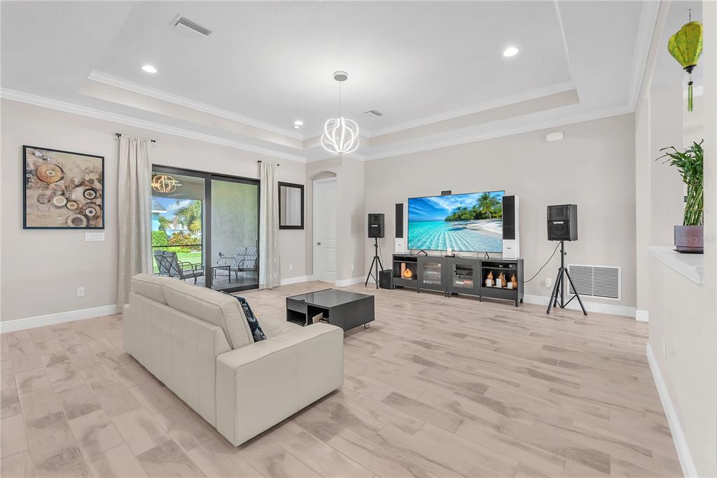A living room features light wood-look tile flooring, a tray ceiling, and a sliding glass door — 814 TIRANO WAY, SUN CITY CENTER, FL
