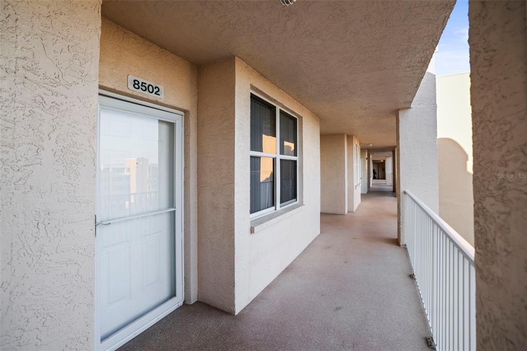 An exterior view of an apartment building hallway with a white door and window — 6495 SHORELINE DRIVE UNIT 8502, ST PETERSBURG, FL