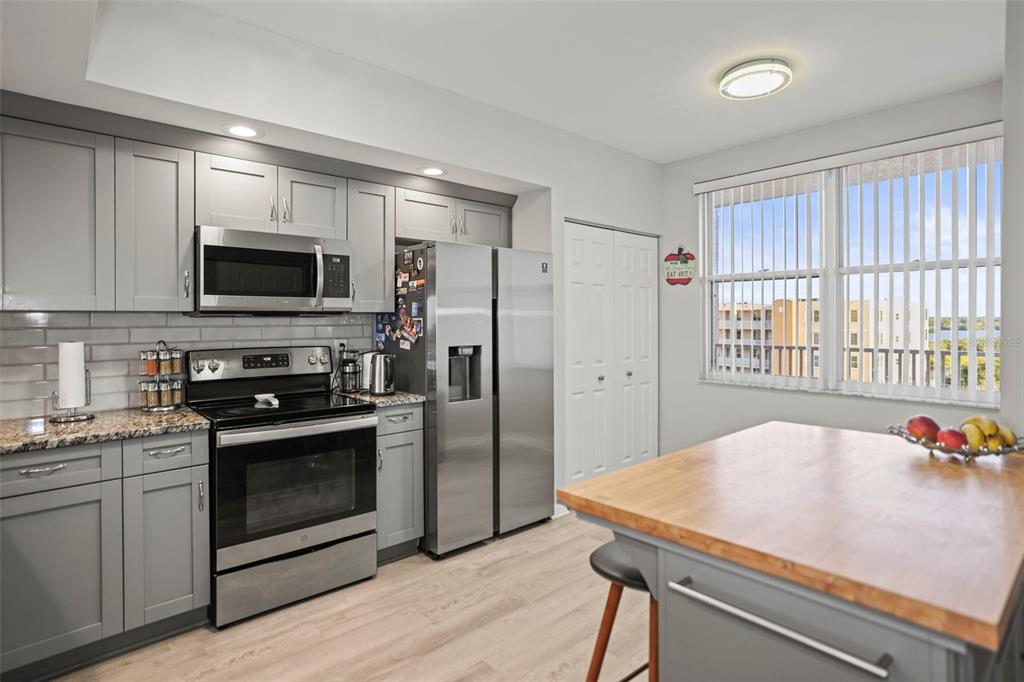 A kitchen with gray cabinets, stainless steel appliances, a wood-topped island, and a large window — 6495 SHORELINE DRIVE UNIT 8502, ST PETERSBURG, FL