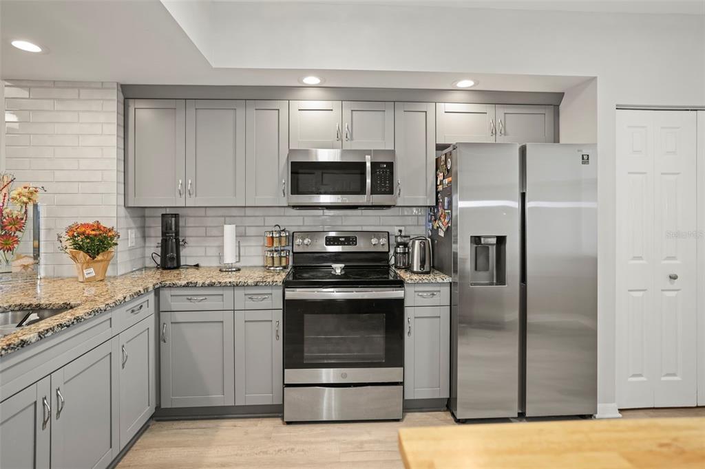 A kitchen features gray cabinets, stainless steel appliances, granite countertops, and a white subway tile backsplash — 6495 SHORELINE DRIVE UNIT 8502, ST PETERSBURG, FL