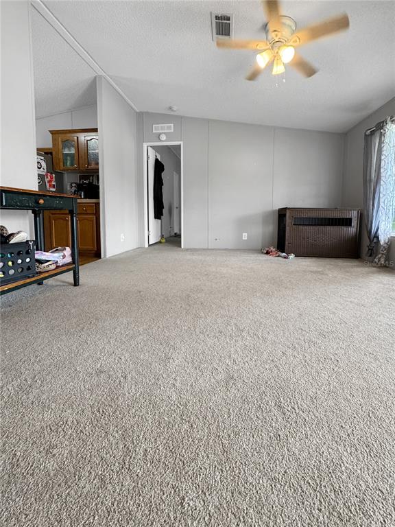 A carpeted living room features a ceiling fan, a doorway to another room, and kitchen cabinetry — 1113 BIG OAK DRIVE, LAKE WALES, FL