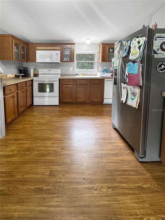 A kitchen with wood cabinets, laminate countertops, white appliances, and wood-look flooring — 1113 BIG OAK DRIVE, LAKE WALES, FL