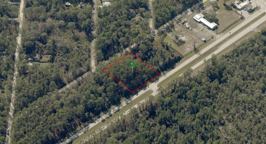 An aerial view shows a rectangular, wooded plot of land outlined in red — 2546 E INTERNATIONAL SPEEDWAY BOULEVARD, DELAND, FL
