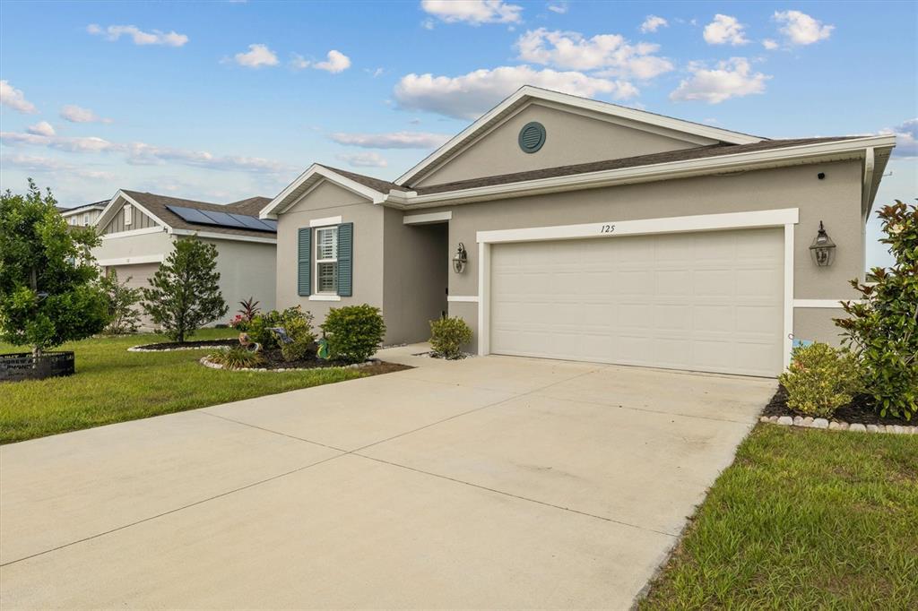 A single-story house with a beige stucco exterior, a two-car garage, and a concrete driveway — 125 CRESTVIEW LANE, DUNDEE, FL