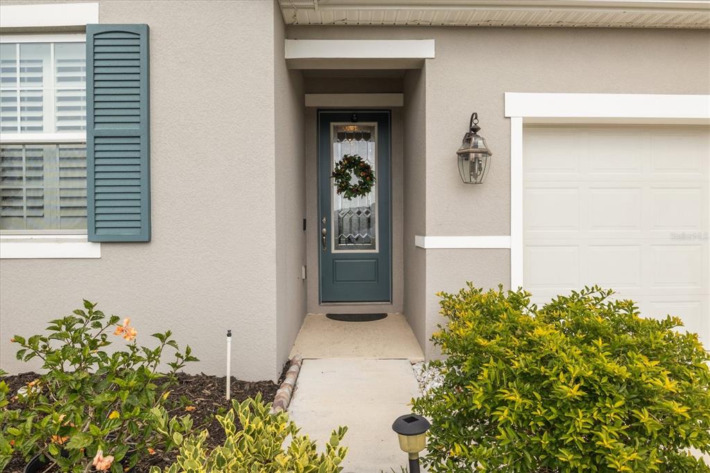 A front entrance features a teal door with a wreath, a lantern, and landscaping — 125 CRESTVIEW LANE, DUNDEE, FL