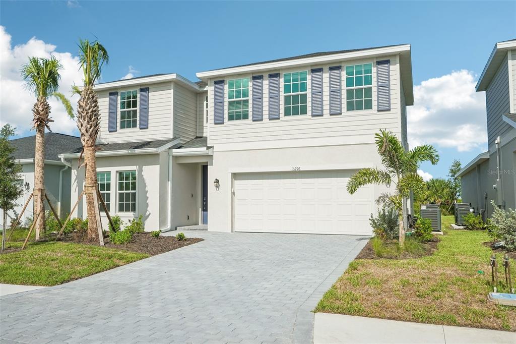 A two-story suburban house with light siding, a two-car garage, and a paved driveway — 13296 GRASSMERE COURT, PUNTA GORDA, FL
