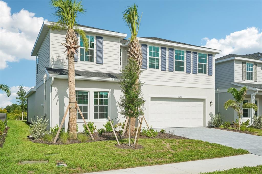A two-story house with light-colored siding, a two-car garage, and two palm trees in front — 13296 GRASSMERE COURT, PUNTA GORDA, FL