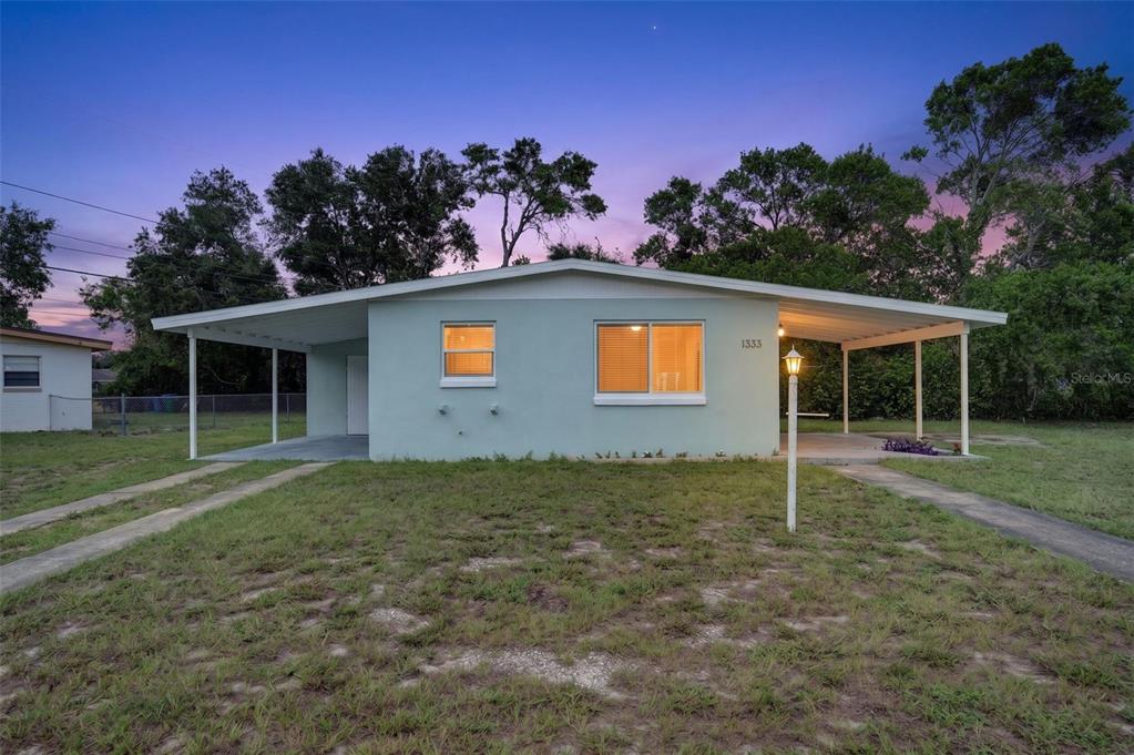 A light blue single-story house features a wide front porch and a large yard — 1333 STILLWATER AVE, DELTONA, FL