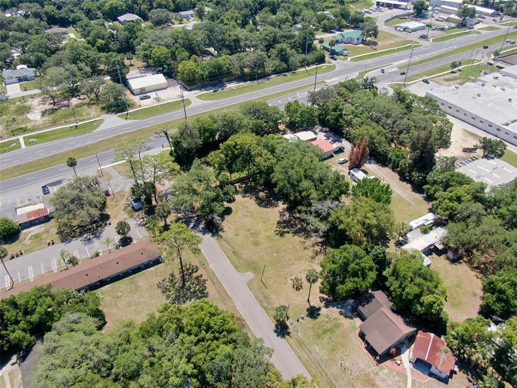 An aerial view shows a vacant lot surrounded by trees, nearby buildings, and a road — Lot 00200 LENORD STREET, UMATILLA, FL