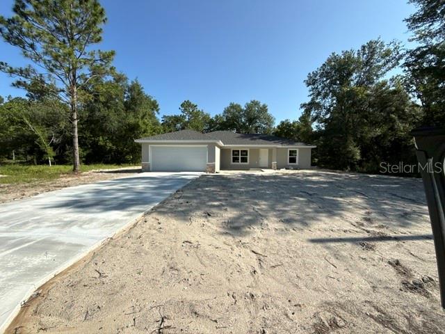 A single-story house with a concrete driveway and sandy yard sits among trees — 8955 SW 139TH STREET, OCALA, FL