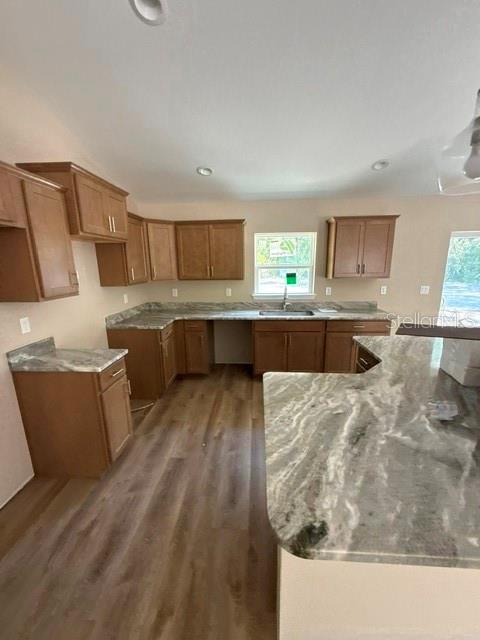 A kitchen features wood cabinets, granite countertops, and wood-look flooring — 8955 SW 139TH STREET, OCALA, FL