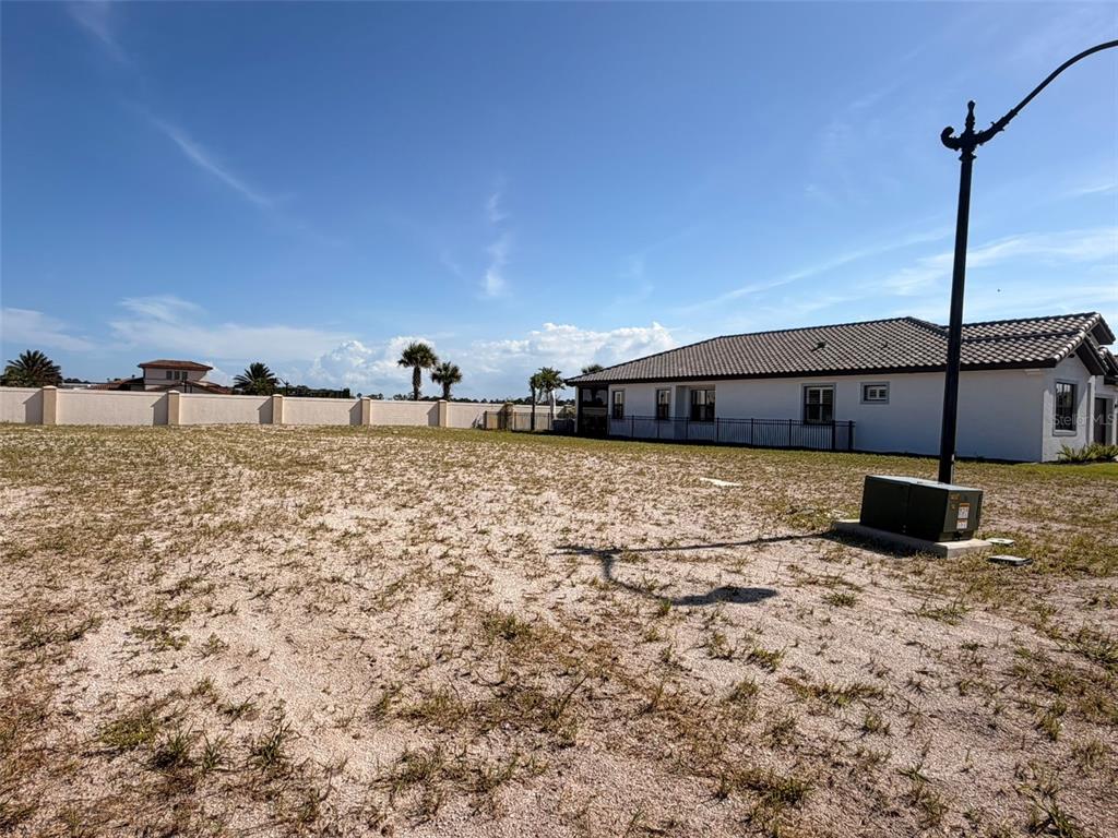 A vacant, sandy lot sits next to a single-story house with a tiled roof — 4 MENORCA WAY, PALM COAST, FL