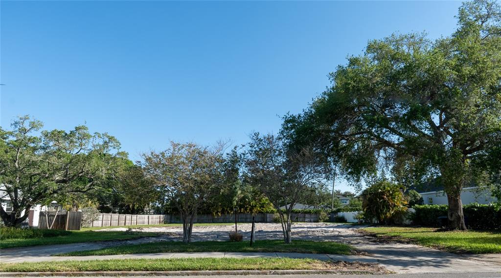 A vacant, sandy residential lot features mature trees and a wooden fence in the background — 1020 SNELL ISLE BOULEVARD NE, ST PETERSBURG, FL
