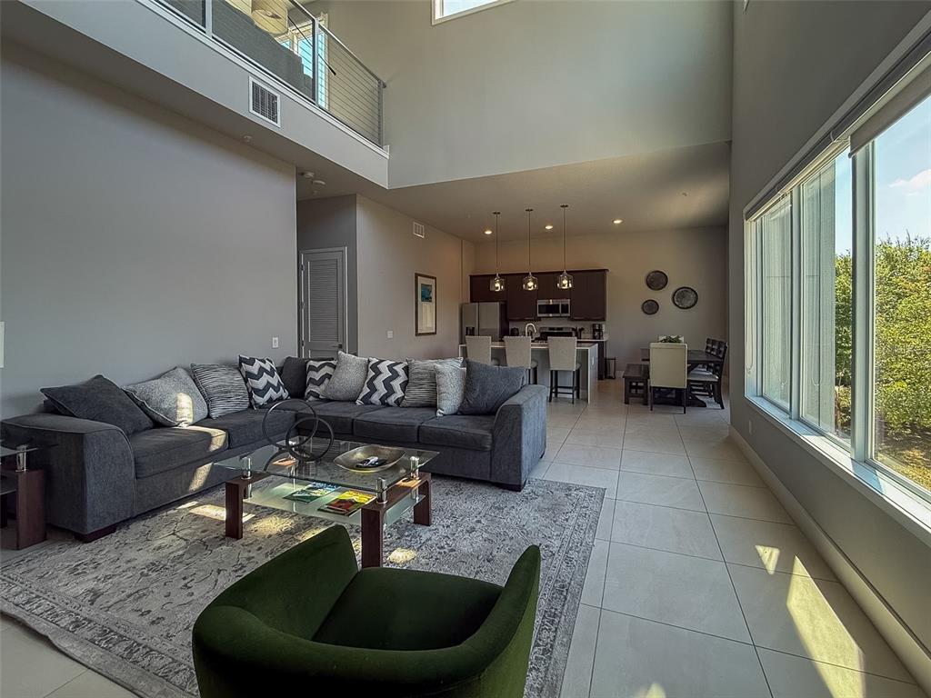 A spacious open-concept living room features a large gray sectional, tile flooring, and high ceilings — 7770 SANDY RIDGE DRIVE UNIT 224, KISSIMMEE, FL
