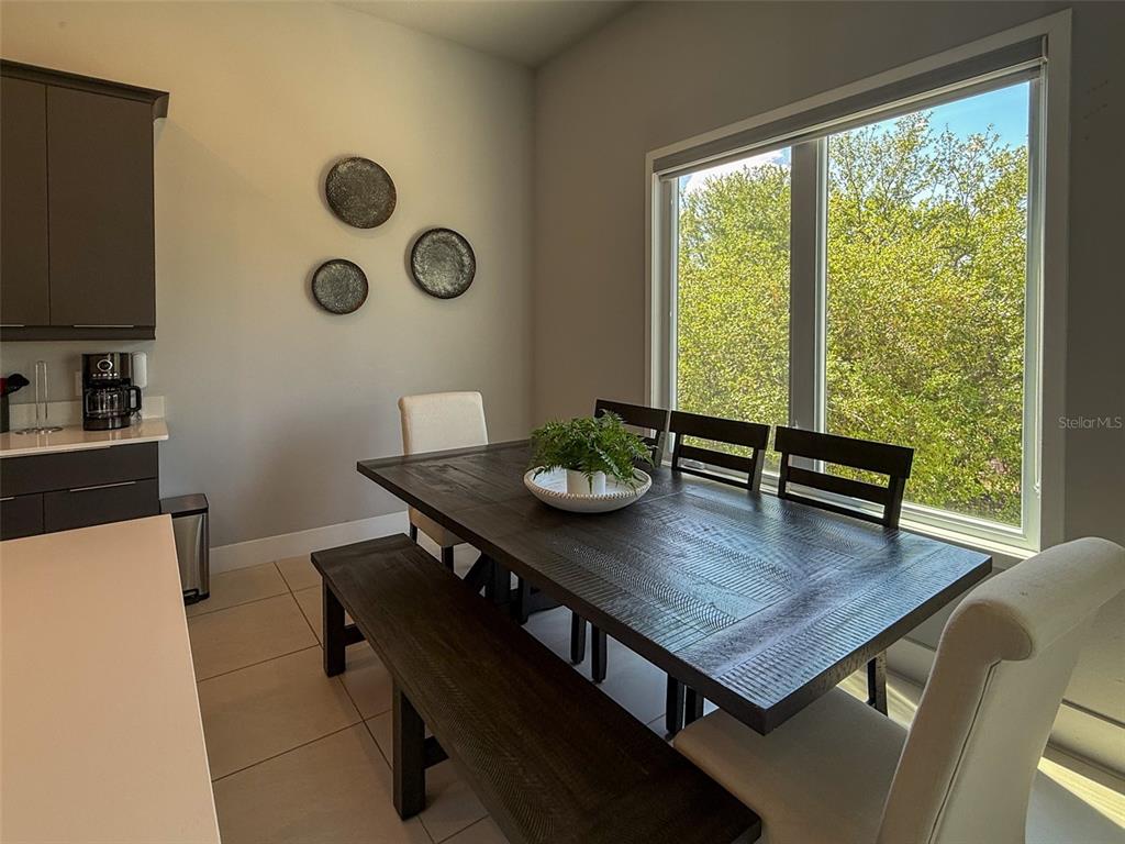 A dining area features a dark wood table with a bench and chairs near a window — 7770 SANDY RIDGE DRIVE UNIT 224, KISSIMMEE, FL