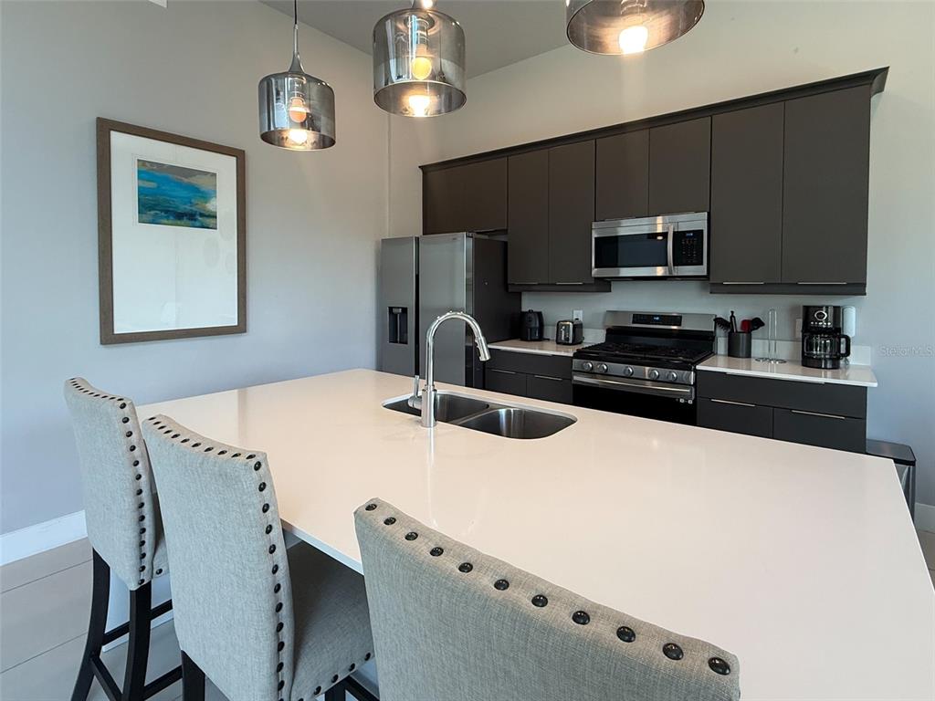 A modern kitchen features a large white island, dark cabinetry, and stainless steel appliances — 7770 SANDY RIDGE DRIVE UNIT 224, KISSIMMEE, FL