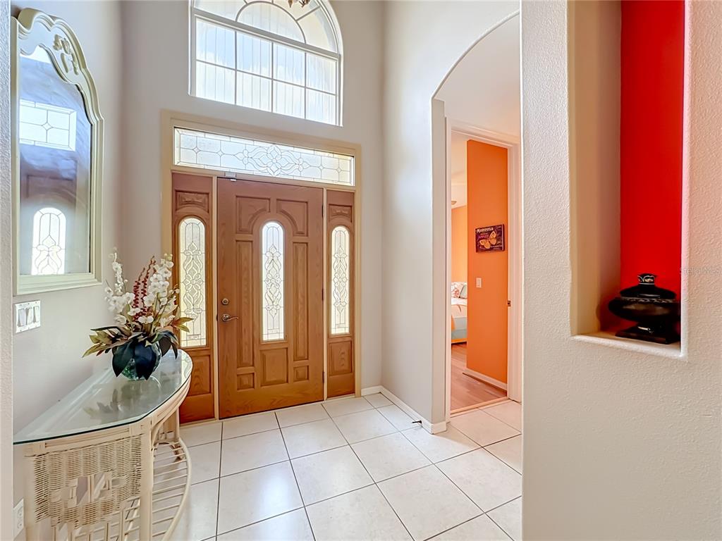 An entryway features a wood front door, tiled floor, arched window, and a decorative wall niche — 6108 LAUREL CREEK TRAIL, ELLENTON, FL