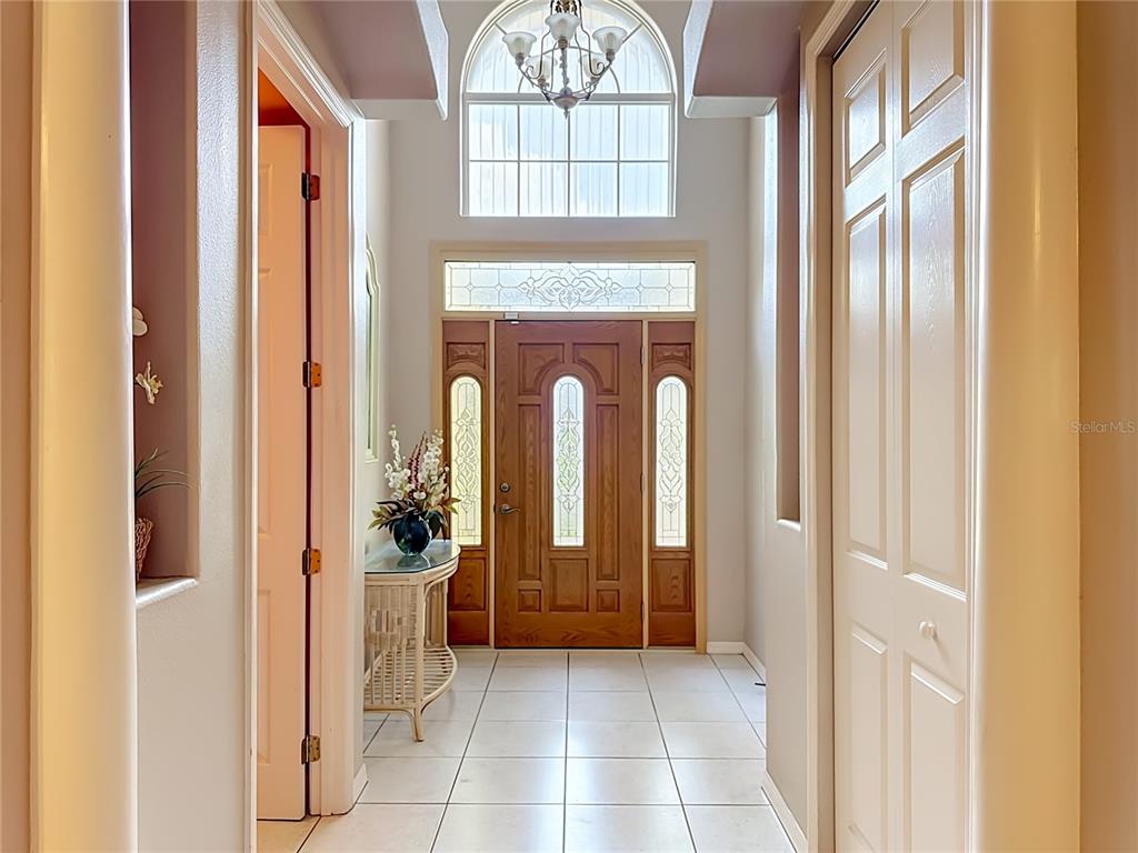 A tiled entryway features a wooden front door with glass panels and a chandelier above — 6108 LAUREL CREEK TRAIL, ELLENTON, FL
