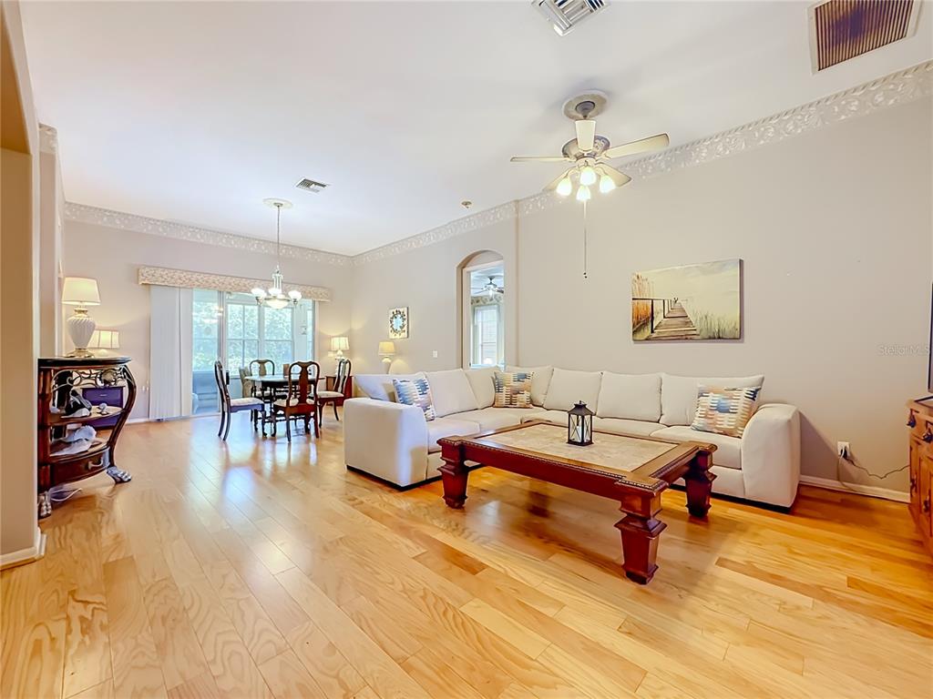 A living room with light wood floors, a sectional sofa, and a dining area — 6108 LAUREL CREEK TRAIL, ELLENTON, FL
