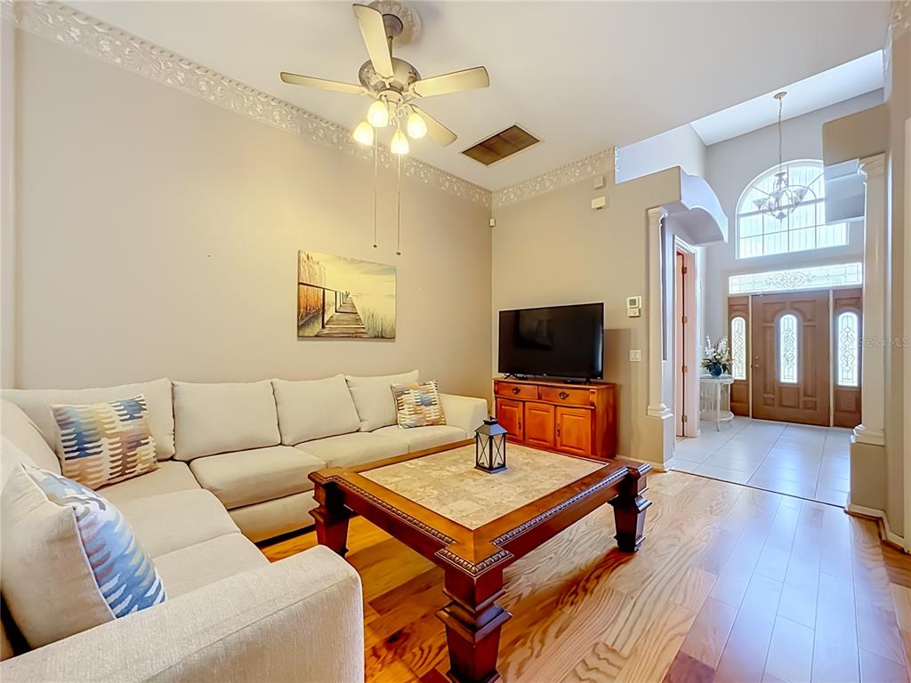 A living room features a sectional sofa, a wooden coffee table, and a television console — 6108 LAUREL CREEK TRAIL, ELLENTON, FL