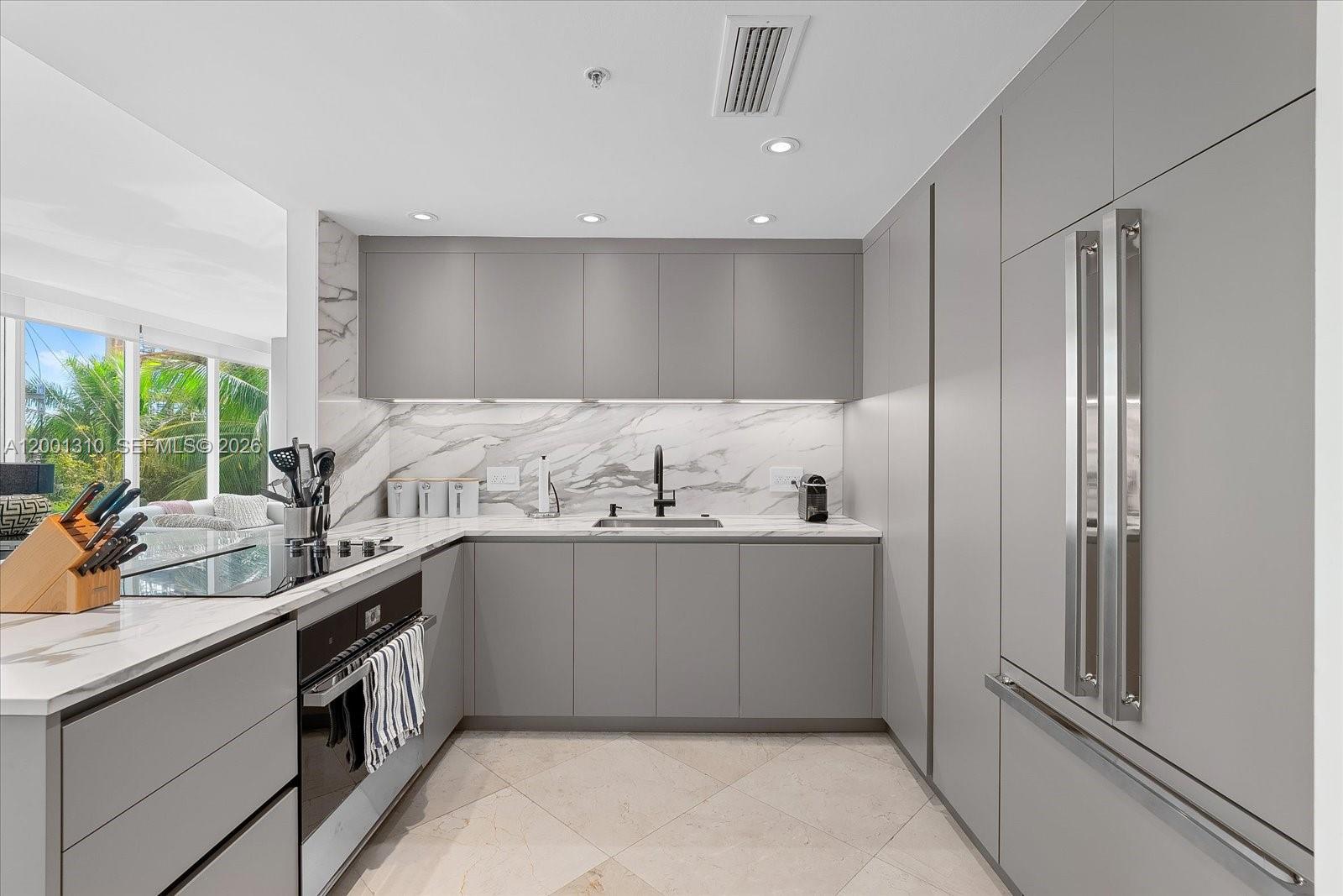 A modern kitchen features gray flat-panel cabinetry, marble-patterned countertops, and stainless steel appliances — 3400 SW 27th Ave # 201, Miami FL 33133, MIAMI, FL