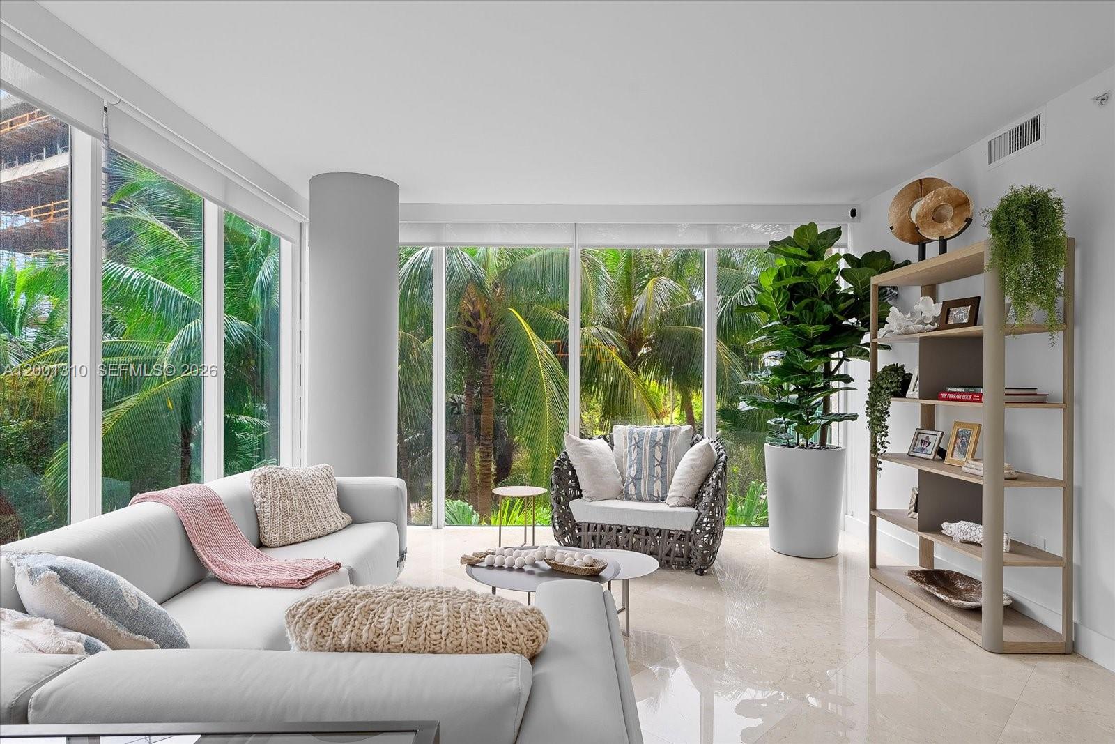 A bright living room features floor-to-ceiling windows, a white sofa, an armchair, and a bookshelf — 3400 SW 27th Ave # 201, Miami FL 33133, MIAMI, FL
