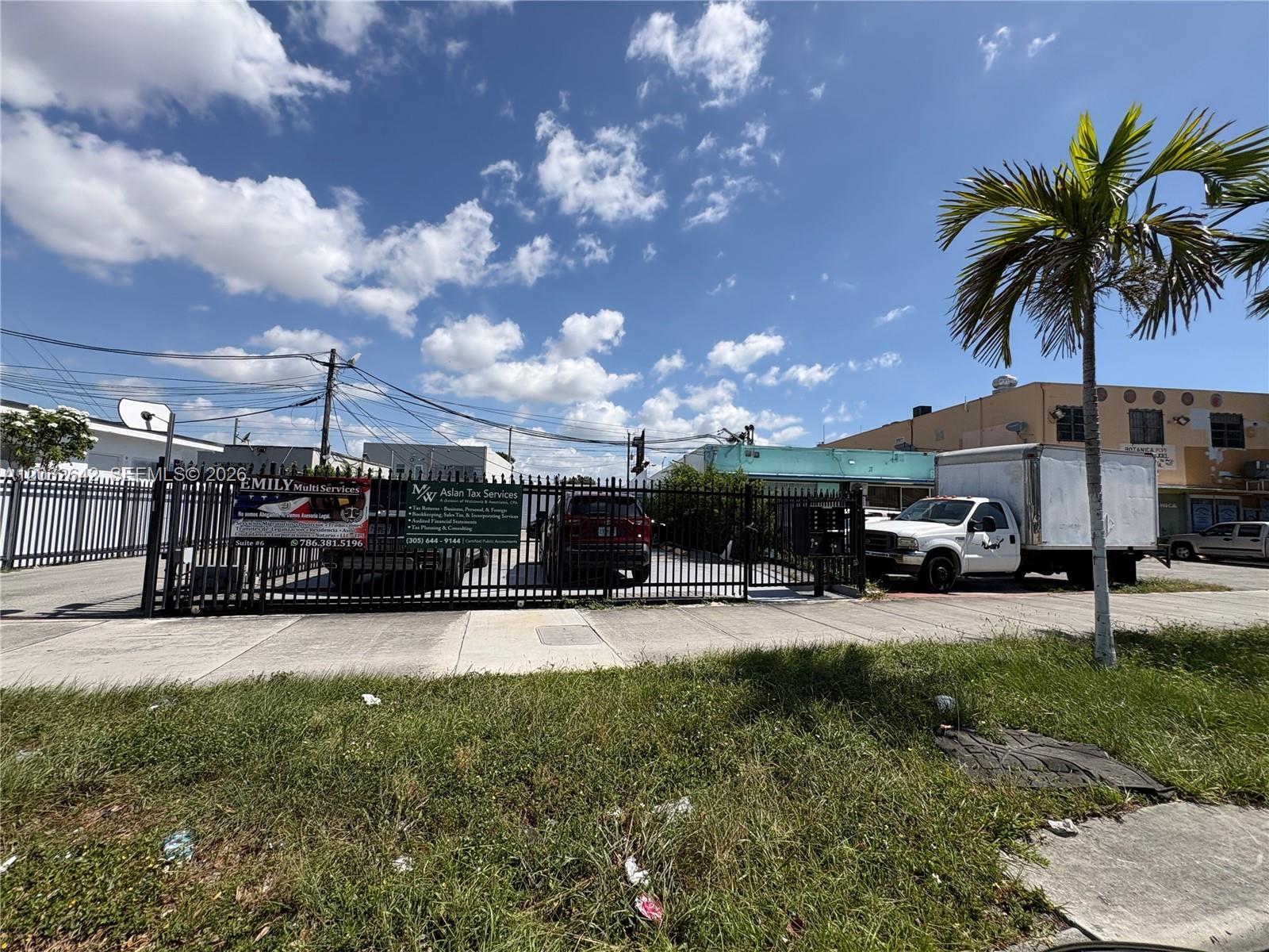 A fenced-in parking lot with a white box truck and business signage on the gate — 1772 W Flagler St, Miami FL 33135, MIAMI, FL
