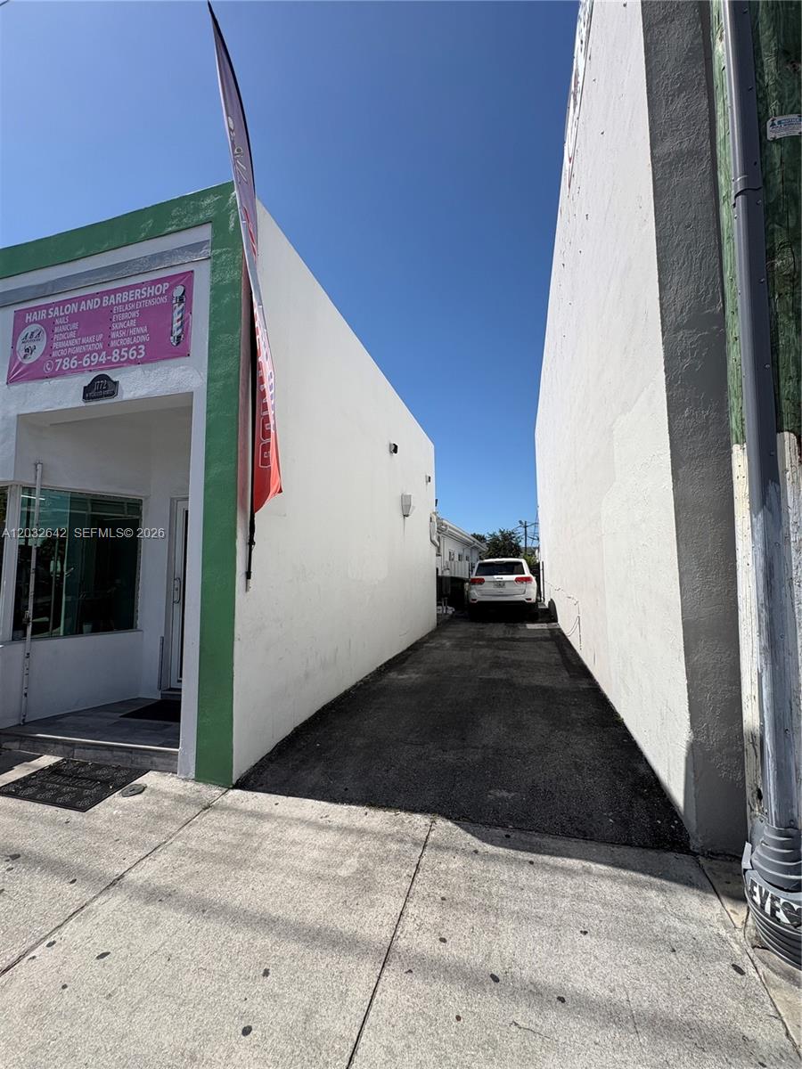 A narrow asphalt driveway sits between two white buildings with a parked white SUV — 1772 W Flagler St, Miami FL 33135, MIAMI, FL