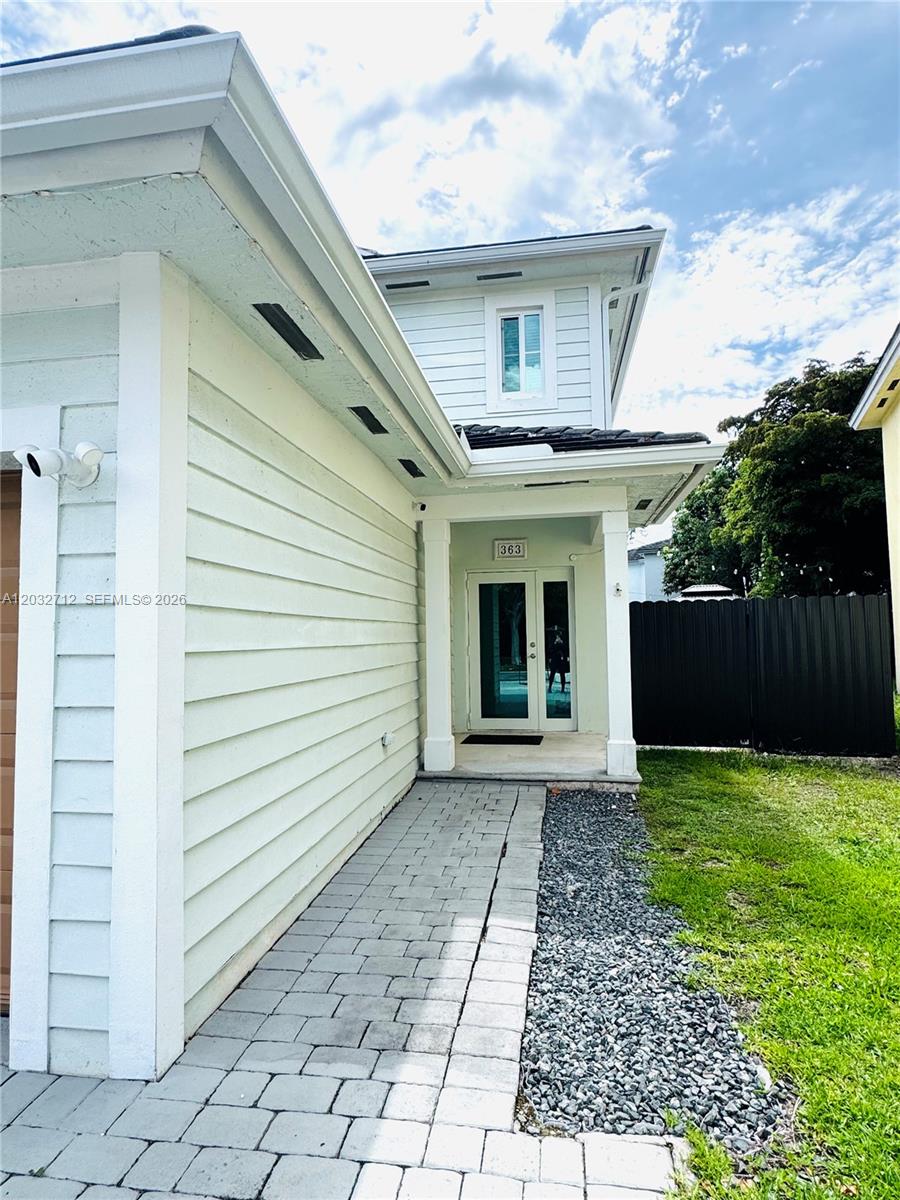 A light-colored house exterior features a paved walkway leading to a glass-paneled front door — 363 NE 35th Ter, Homestead FL 33033, HOMESTEAD, FL