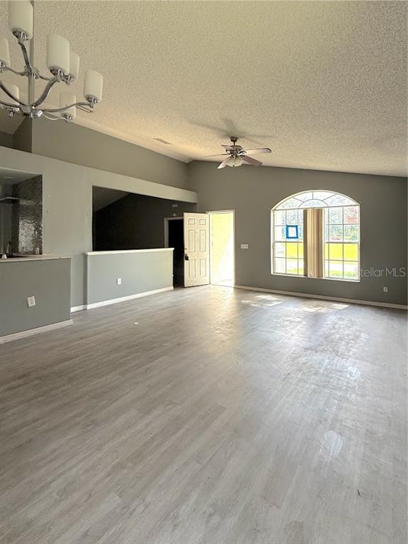 A spacious living area features light wood-look flooring, a vaulted ceiling, and a large arched window — 6313 LIVEWOOD OAKS DRIVE, ORLANDO, FL
