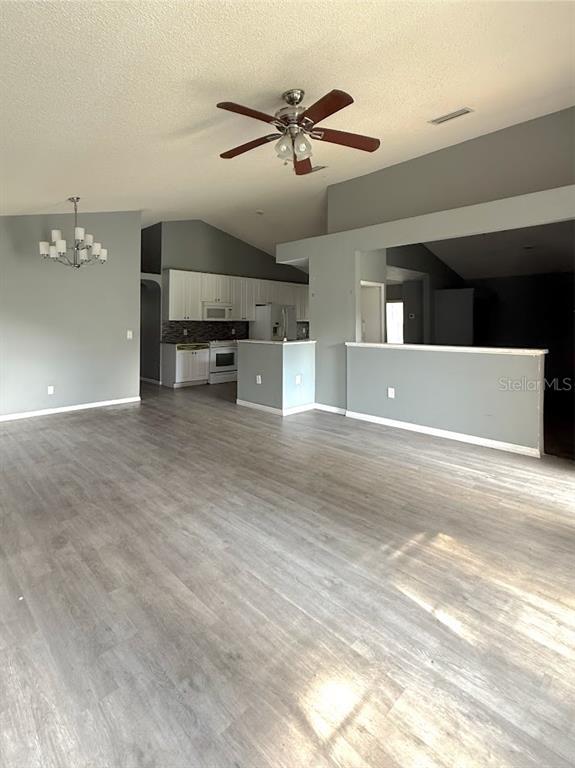 An open-concept living area features light gray walls, wood-look flooring, and a kitchen with white cabinets — 6313 LIVEWOOD OAKS DRIVE, ORLANDO, FL