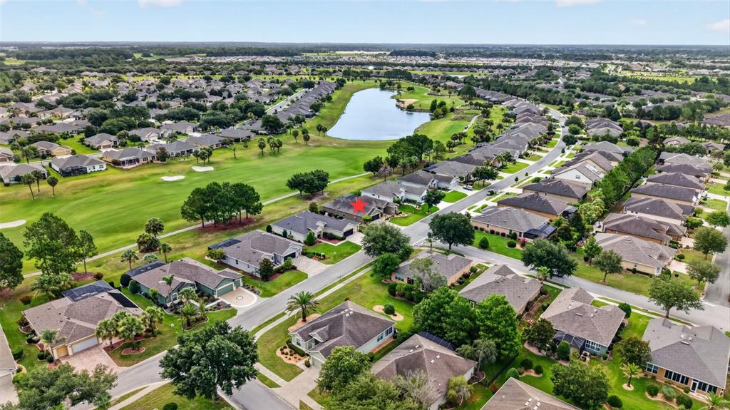 An aerial view shows a residential neighborhood with houses surrounding a golf course and lake — 7419 SW 97TH TERRACE ROAD, OCALA, FL
