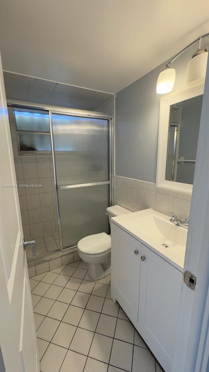 A bathroom features a white vanity, a toilet, and a shower with sliding glass doors — 1421 NW 45th St # 5, Deerfield Beach FL 33064, DEERFIELD BEACH, FL