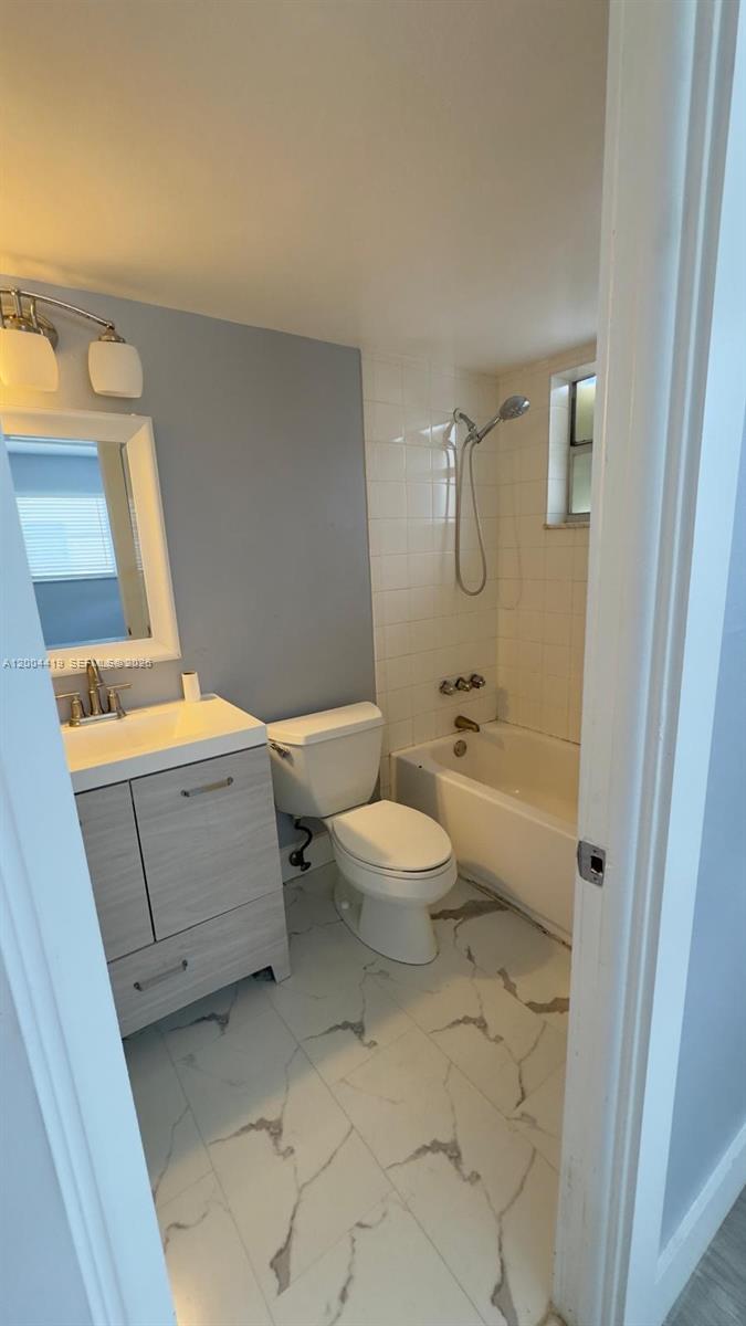 A bathroom features a vanity, toilet, and a tiled shower-tub combination with marble-look flooring — 1421 NW 45th St # 5, Deerfield Beach FL 33064, DEERFIELD BEACH, FL