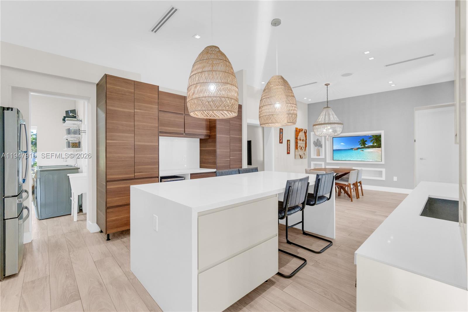 A modern kitchen features a white island, wood cabinetry, and two large woven pendant lights — 760 NE 115th St, Biscayne Park FL 33161, BISCAYNE PARK, FL